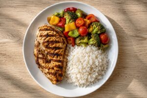 plate of grilled chicken, vegetables, and a modest portion of rice